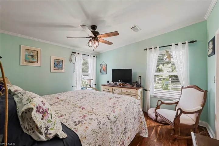 Interior room featuring wood-finish flooring, light green walls, and white crown molding