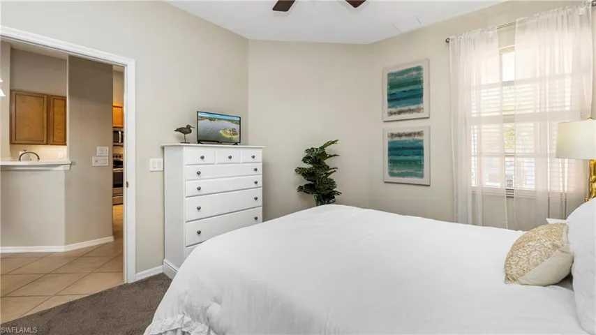 Bedroom with light tile patterned floors, a ceiling fan, and light carpet