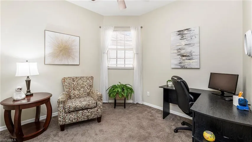 Carpeted office space with baseboards and a ceiling fan