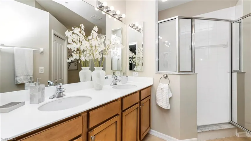 Full bath featuring double vanity and a shower stall