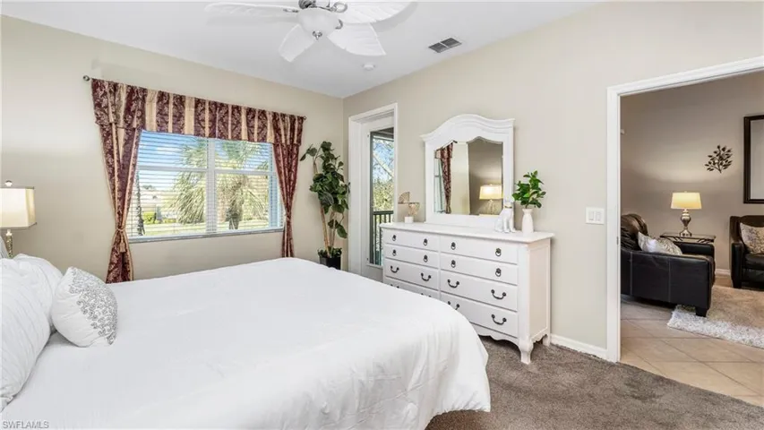 Bedroom with light carpet, a ceiling fan, and light tile patterned flooring
