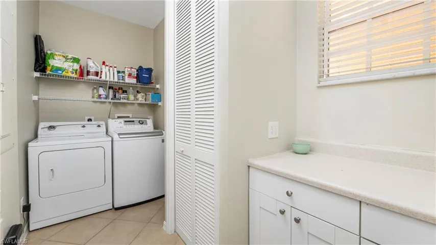 Laundry room with washing machine and dryer and light tile patterned flooring