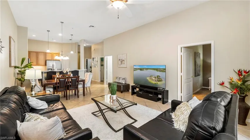 Living area featuring ceiling fan, a high ceiling, light tile patterned floors, and recessed lighting