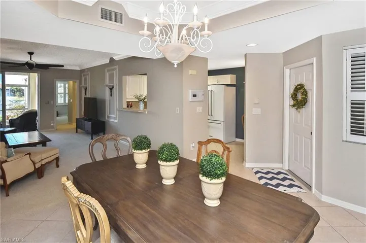 Dining room featuring light tile patterned floors, baseboards, ceiling fan with notable chandelier, and visible vents
