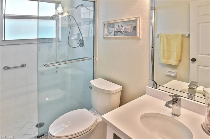 Full bath with vanity, toilet, a textured wall, and a stall shower