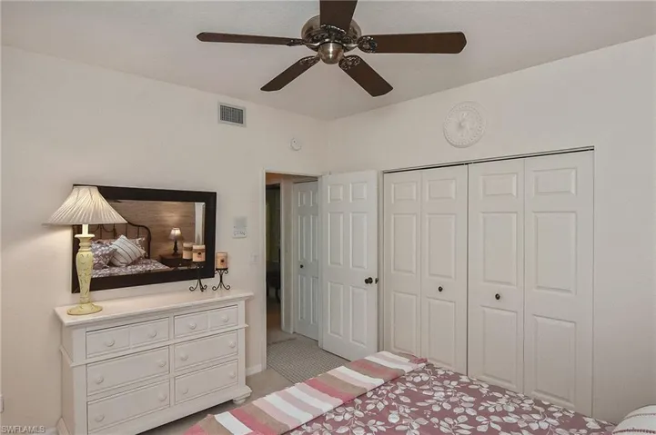 Bedroom with ceiling fan, visible vents, and a closet
