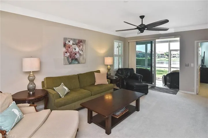 Living room with baseboards, ornamental molding, a ceiling fan, and light carpet