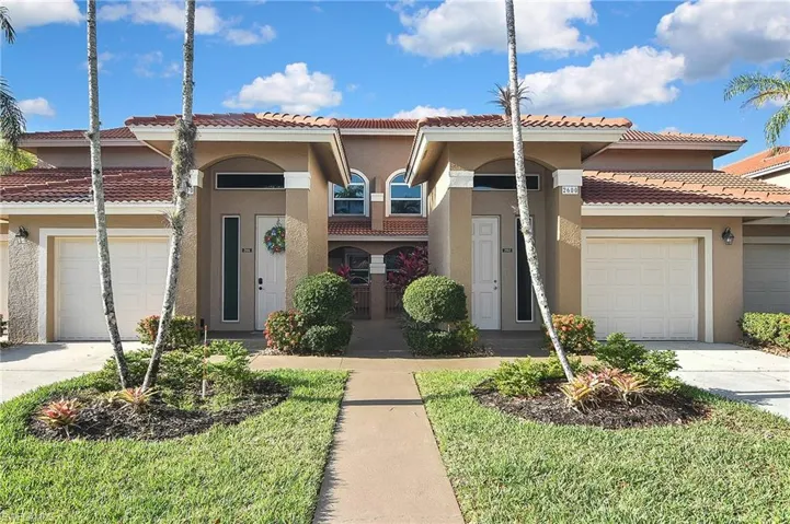 View of front of property with concrete driveway, a tiled roof, an attached garage, and stucco siding
