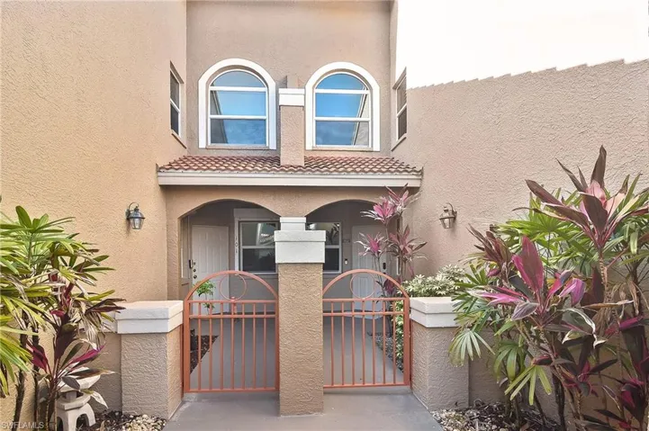 View of front of house with covered porch, a tile roof, a gate, and stucco siding
