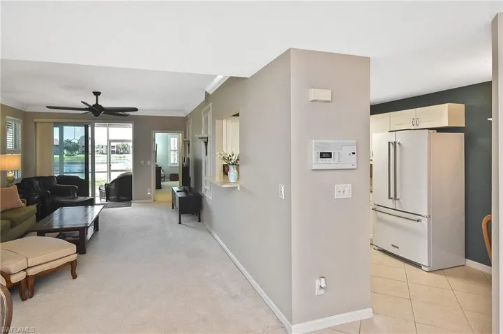 Living room featuring light tile patterned floors, baseboards, ornamental molding, and ceiling fan