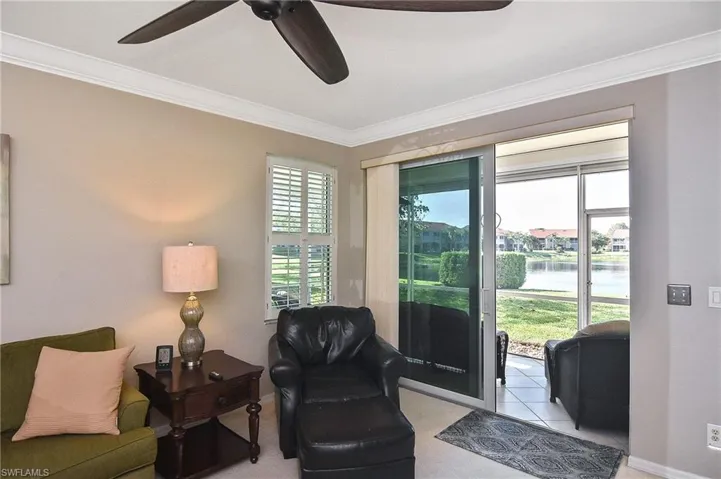 Sitting room with crown molding, a water view, ceiling fan, and baseboards