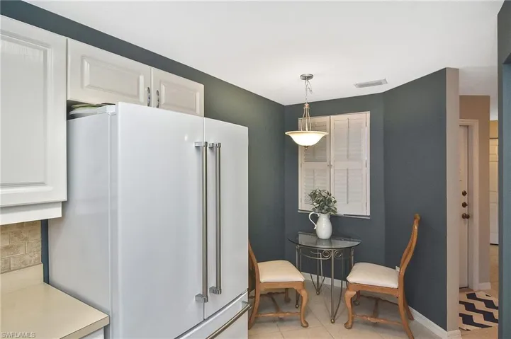 Kitchen with white cabinets, visible vents, pendant lighting, and high end white refrigerator