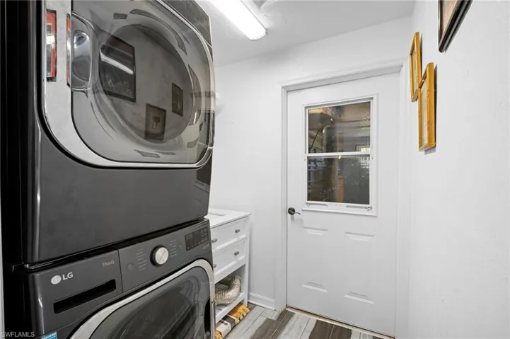Laundry room featuring stacked washer / dryer and light wood-style floors