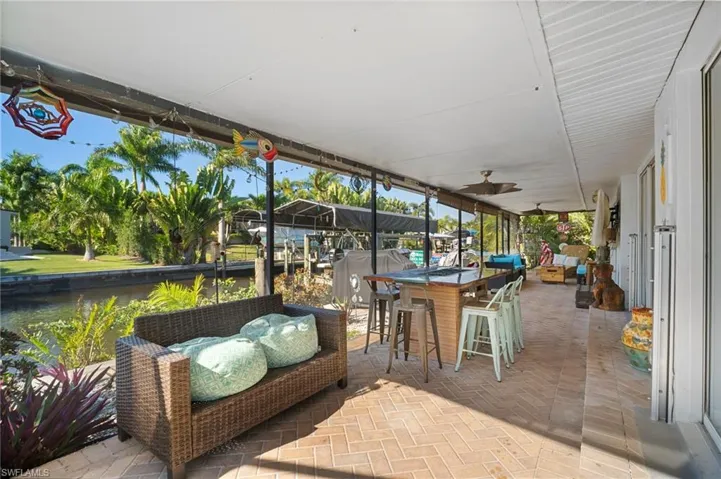 Sunroom / solarium with a patio area, an outdoor lounge area with bar, ceiling fan, and a water view