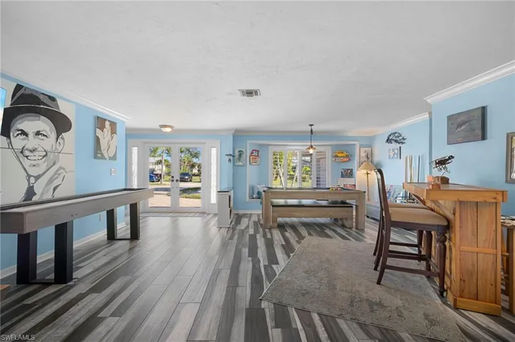 Dining space featuring french doors, healthy amount of natural light, wood finished floors, ornamental molding, and a textured ceiling