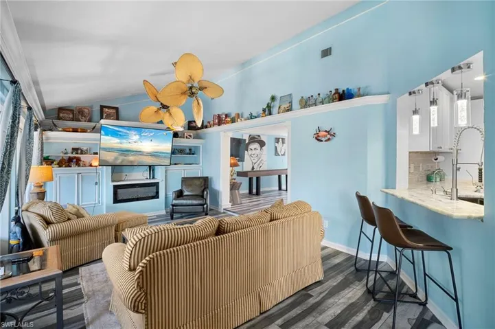 Living room featuring lofted ceiling, dark wood-style floors, and ceiling fan