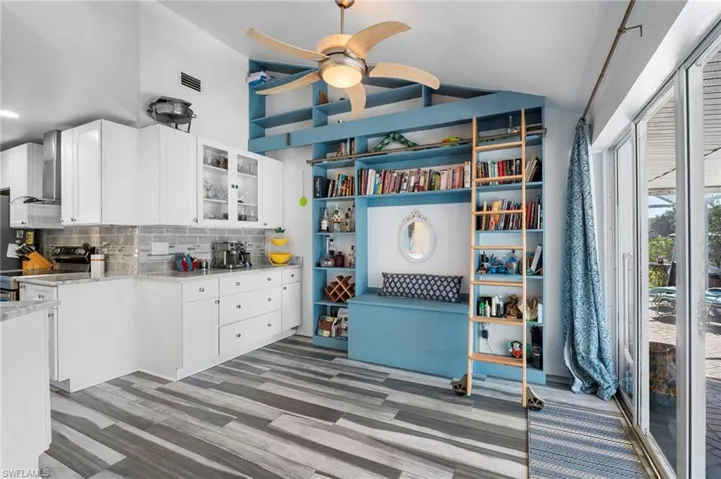 Kitchen featuring white cabinets, decorative backsplash, glass fronted cabinets, electric range, and light wood-type flooring