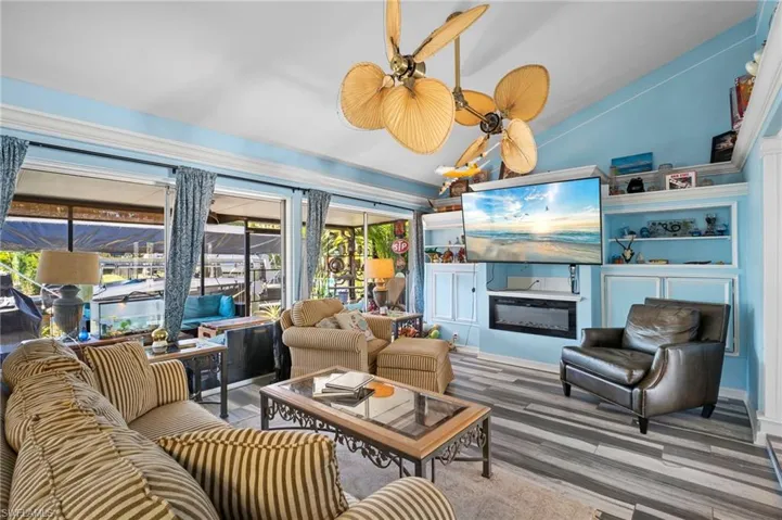 Living room with a glass covered fireplace, wood finished floors, and vaulted ceiling