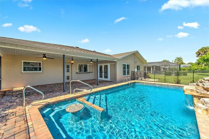 View of pool with a patio, glass enclosure, and ceiling fan