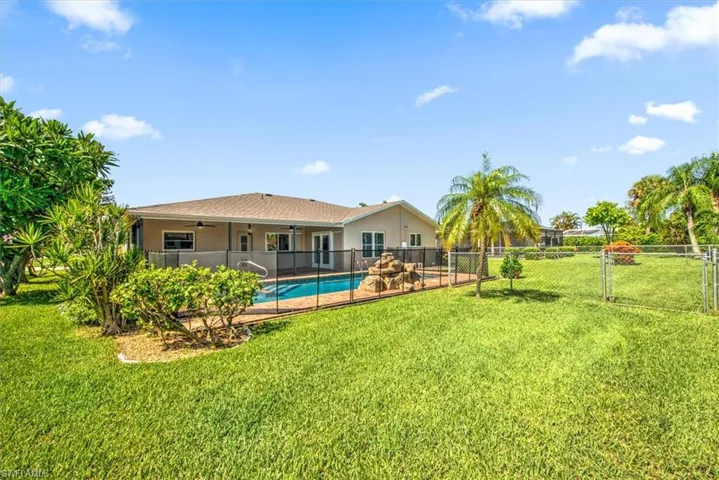 Back of property featuring a fenced in pool and a lawn