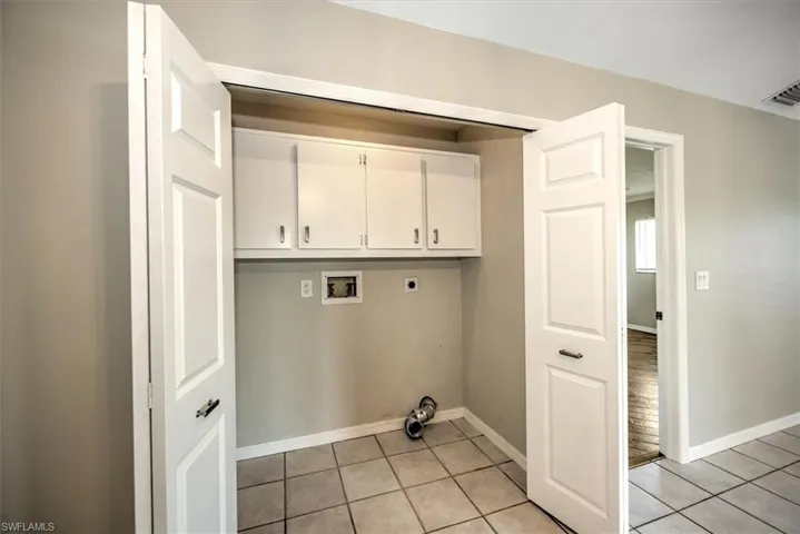 Laundry area featuring cabinets, hookup for a washing machine, hookup for an electric dryer, and light tile patterned flooring