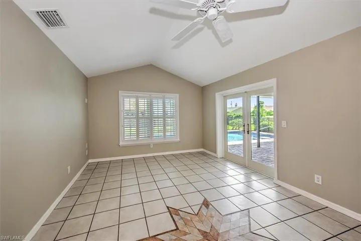 Tiled empty room featuring french doors, ceiling fan, and lofted ceiling