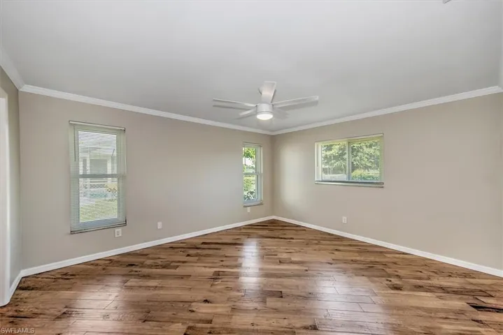 Unfurnished room with ceiling fan, wood-type flooring, and ornamental molding