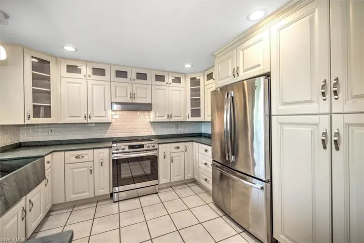 Kitchen with stainless steel refrigerator, wall oven, backsplash, and light tile patterned floors