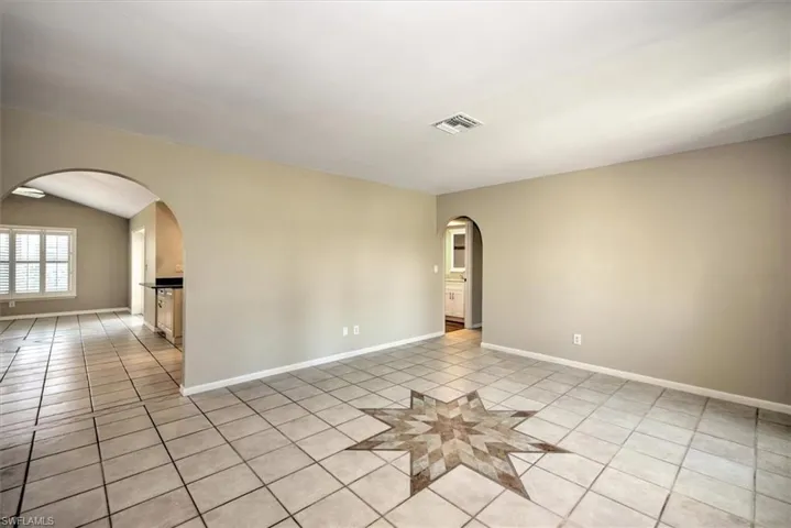 Empty room featuring light tile patterned flooring and vaulted ceiling