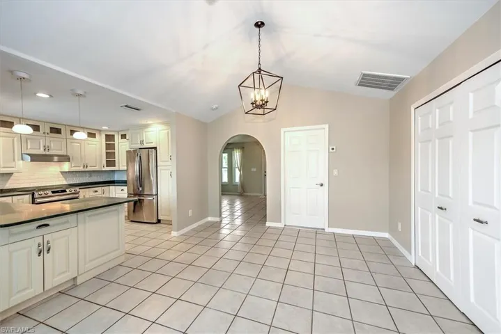 Kitchen featuring lofted ceiling, light tile patterned flooring, hanging light fixtures, and stainless steel appliances