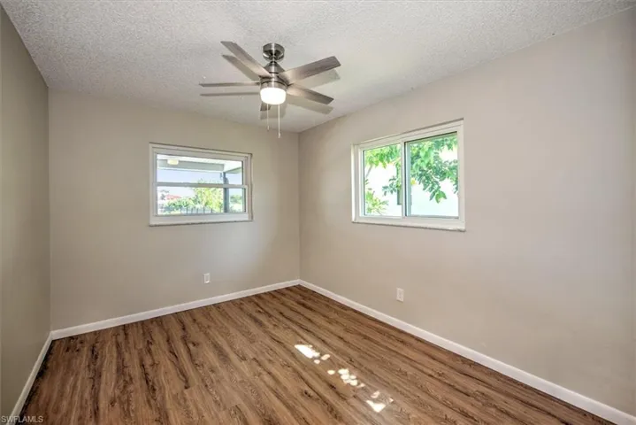 Spare room with ceiling fan, wood-type flooring, and a textured ceiling