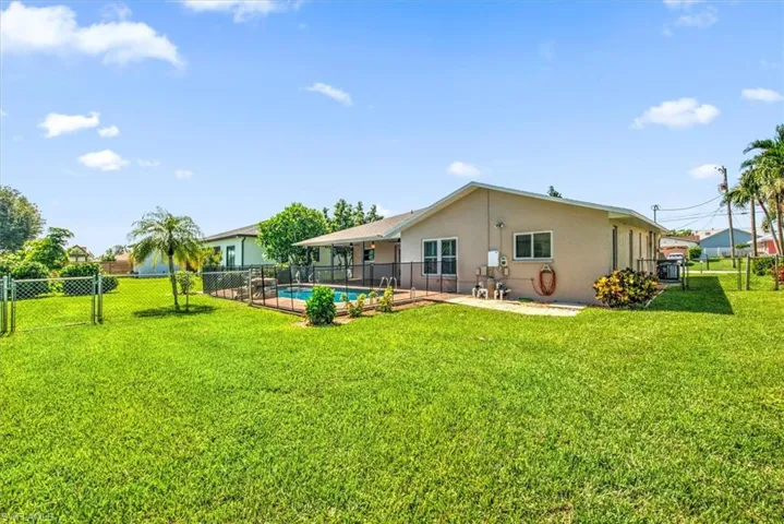Rear view of house featuring a patio, a yard, and a fenced in pool