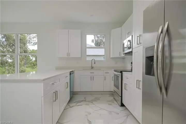 Kitchen with a healthy amount of sunlight, white cabinetry, and stainless steel appliances