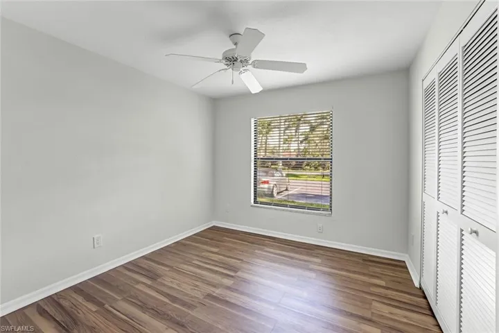 Unfurnished bedroom featuring wood finished floors, a closet, baseboards, and a ceiling fan