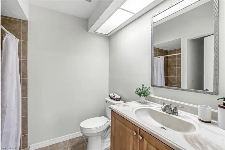 Full bath featuring tile patterned floors, toilet, a tile shower, vanity, and baseboards