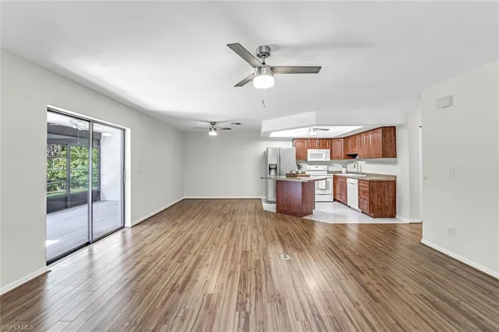 Unfurnished living room with ceiling fan, light wood-style flooring, baseboards, and a sink