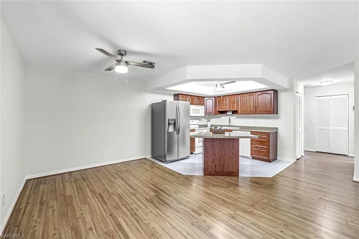 Kitchen with white appliances, ceiling fan, light wood-style floors, and a kitchen island
