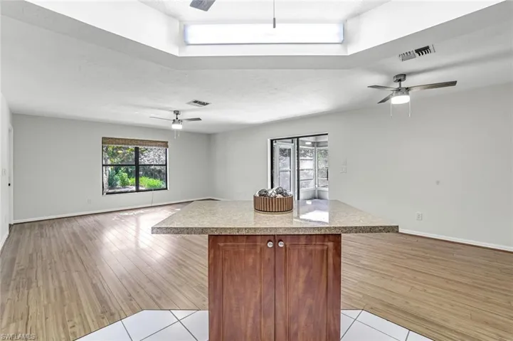 Kitchen with a ceiling fan, open floor plan, a center island, light countertops, and a textured ceiling
