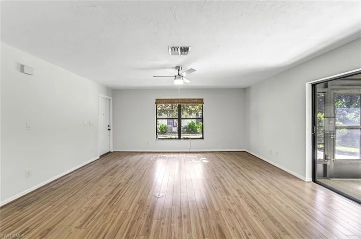 Unfurnished room featuring ceiling fan, wood finished floors, baseboards, and a textured ceiling
