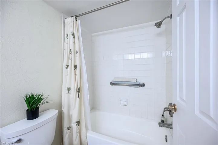 Bathroom with shower / bath combination with curtain and toilet