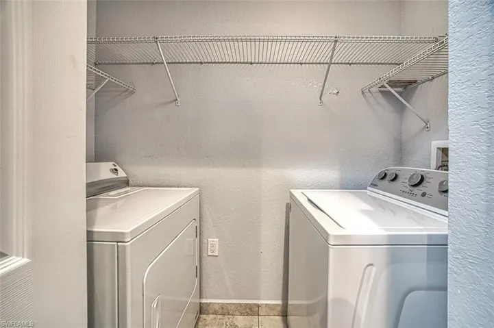 Clothes washing area featuring independent washer and dryer and light tile patterned floors
