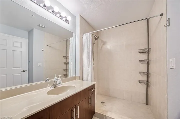 Bathroom featuring a shower with shower curtain, a textured ceiling, and vanity