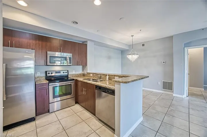Kitchen with kitchen peninsula, stainless steel appliances, and light stone countertops