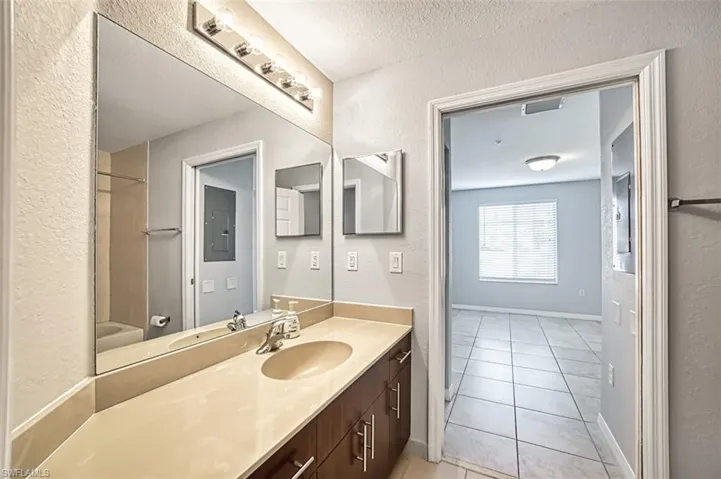 Bathroom with tile patterned floors, vanity, a textured ceiling, electric panel, and  shower combination