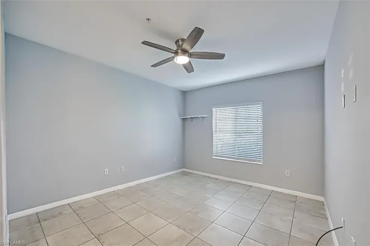 Tiled spare room featuring ceiling fan