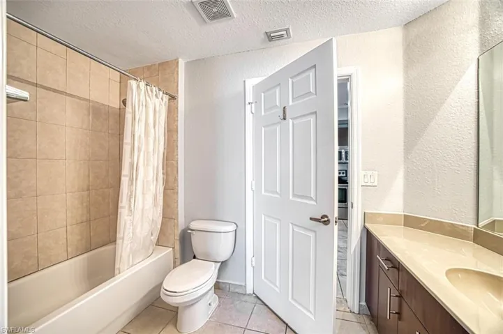 Full bathroom with toilet, tile patterned floors, vanity, a textured ceiling, and shower / tub combo with curtain