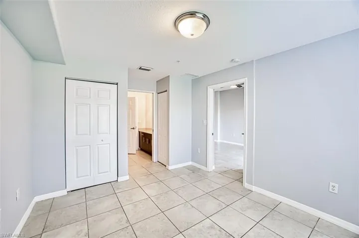 Unfurnished bedroom featuring light tile patterned floors and connected bathroom