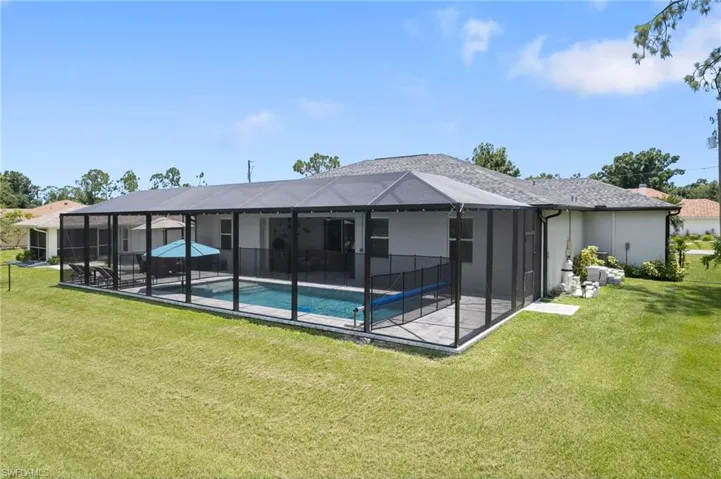 Rear view of house featuring a patio, a lanai, and a lawn