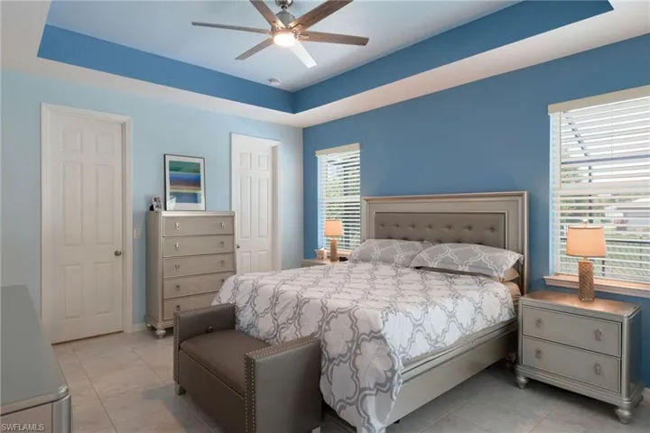 Bedroom featuring light tile patterned flooring, ceiling fan, and a raised ceiling