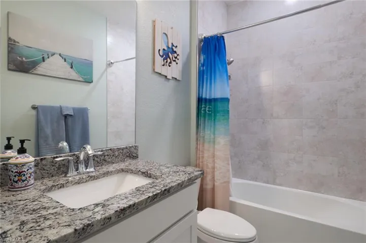 Full bathroom featuring shower / bathtub combination with curtain, toilet, and vanity